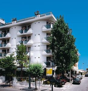 a large white building with cars parked in front of it at Hotel ABC in Riccione