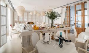 a dining room with white tables and white chairs at Hotel Es Marès in Sant Francesc Xavier