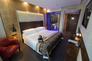 Felix Hotel في فالس: غرفة فندقية بسرير كبير وكرسي