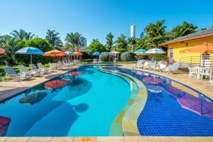 uma grande piscina com cadeiras e guarda-sóis em Pousada Paiol em Atibaia