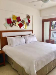 Un dormitorio con una cama blanca con cartas en la pared en Ambiance Suites, en Cancún