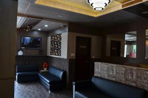 a waiting room with two blue leather couches and a tv at Hotel Sartaj in Dera Bassi