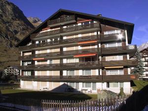 ein großes Gebäude mit einem Zaun davor in der Unterkunft Haus Granit in Zermatt