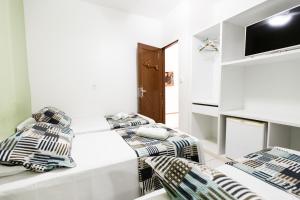 a white room with two beds and a flat screen tv at Pousada do Mano in Fernando de Noronha