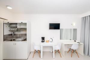 a kitchen with white cabinets and a white table and chairs at Golden View Studios in Líndos