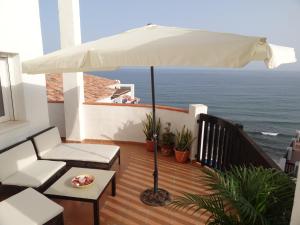uma varanda com um guarda-chuva branco e o oceano em Beachfront Penthouse Apartment with Large Terrace and Breathtaking Sea Views close to Marbella Spain em Mijas Costa