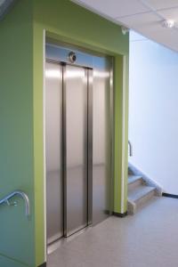 an elevator in a building with green walls and stairs at Lahti Lehti House in Lahti