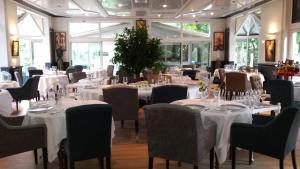 a restaurant with tables and chairs with white tablecloths at Hotel Le Rivage in Olivet