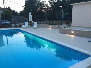 een zwembad met 2 stoelen en een parasol bij Guest House Punta Grzan in Petrcane