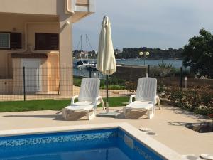 two chairs and an umbrella next to a swimming pool at Guest House Punta Grzan in Petrcane