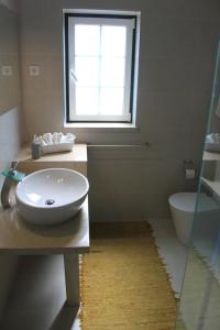 a bathroom with a sink and a toilet and a window at Avo das Bolachas nº 12 in Nazaré