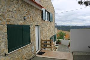 a stone house with green doors and a gate at Avo das Bolachas nº 12 in Nazaré