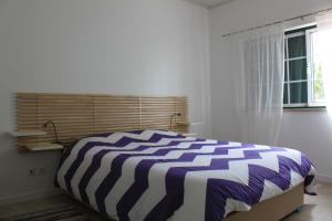 um quarto com uma cama com um edredão listrado em Avo das Bolachas nº 12 em Nazaré