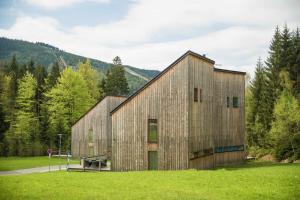 a large wooden building in a field with trees at Chalet Harrachov & Wellness Grotta Spa free in Harrachov