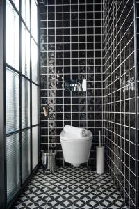 a bathroom with a toilet and a black tiled wall at Lemon Tree Stay in Faro