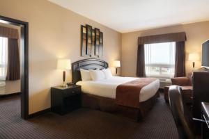 a hotel room with a bed and a chair at Days Inn by Wyndham Innisfail in Innisfail +26 photos