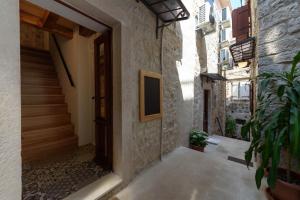 an alley with a door in a building with a plant at Apartments & Rooms Tiramola - Old Town in Trogir