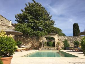 - une piscine en face d'un mur en pierre dans l'établissement Domaine Les Martins - Gordes, à Gordes