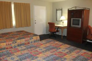 a hotel room with two beds and a desk and a television at Golden Chain Motel in Grass Valley