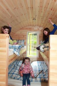 dwie dziewczynki i mała dziewczynka siedząca na łóżku piętrowym w obiekcie Coach Field Camp w mieście Camp