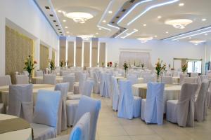 un salón de banquetes con mesas blancas y sillas blancas en King Hotel, en Peje
