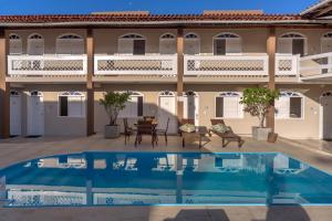 a house with a swimming pool in front of a building at Pousada Jangadeiro in Porto Seguro
