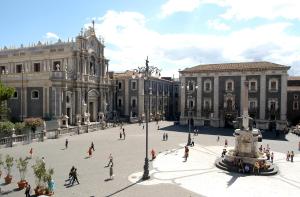 a group of people walking around a plaza in front of a building at Naturalmente abitare in Catania