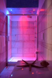 a bathroom with pink lighting and a shower with a tub at B&B Anemos in Morciano di Leuca