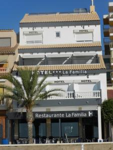 a building with a palm tree in front of it at Hotel La Familia in El Campello