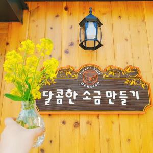 a sign on a wall with a vase of flowers at Sweetsalt in Seogwipo