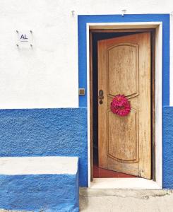 a blue and white building with a door with a wreath on it at A Casa da Avó Leonor in Idanha-a-Nova