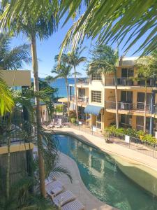 una piscina frente a un complejo con palmeras en Beachside Holiday Apartments, en Port Macquarie