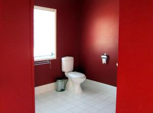 a red bathroom with a toilet and a window at Neds Cabin in Amiens