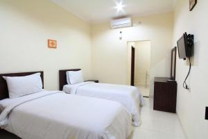 una camera d'albergo con due letti e una televisione di Surya Inn a Kuta