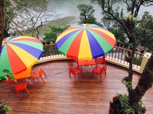 2 sombrillas y sillas coloridas en el patio en The Woods en Nainital