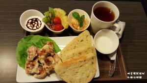 a plate of food with chicken and bread and a cup of tea at Bai Ji Yi B&B in Hengchun