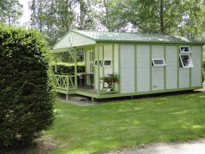 un cobertizo verde con porche en un patio en Camping les Pinasses, en La Chapelle