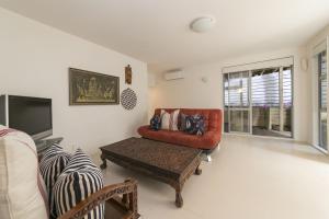 a living room with a red couch and a tv at Ted's Cottage near Little Oneroa Beach by Waiheke Unlimited in Oneroa