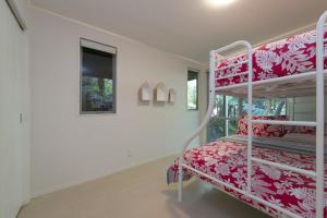 ein Schlafzimmer mit Etagenbetten in einem weißen Zimmer in der Unterkunft Ted's Cottage near Little Oneroa Beach by Waiheke Unlimited in Oneroa