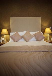 a large bed with four pillows on it with two lamps at Laichmoray Hotel in Elgin