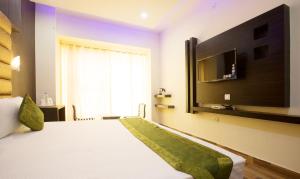 a bedroom with a bed with a television on the wall at Vibhav Grand in Haridwār