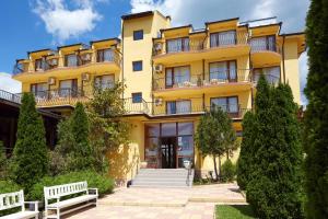 a yellow building with benches in front of it at Family Hotel YALTA Свети Влас in Sveti Vlas