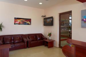 a living room with a brown leather couch and a tv at Family Hotel YALTA Свети Влас in Sveti Vlas