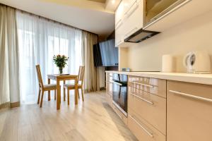 kuchnia ze stołem, 2 krzesłami i oknem w obiekcie Apartment Royal III w mieście Białystok