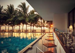 a pool with chairs and a bar with a view of the ocean at Jetwing Blue in Negombo