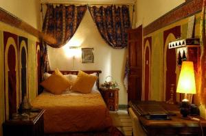 a bedroom with a bed and a desk with a lamp at Riad Dalia in Marrakesh