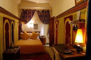 a bedroom with a bed and a desk with a lamp at Riad Dalia in Marrakesh