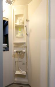 a bathroom with a white refrigerator with a hose at Sumiya Spa & Hotel in Hiroshima