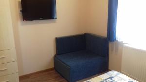 ハイドゥソボスローにあるEszter apartmanházの青い椅子、壁にテレビが備わる客室です。