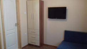 ハイドゥソボスローにあるEszter apartmanházのベッドルーム(壁にテレビ付)、クローゼットが備わります。
